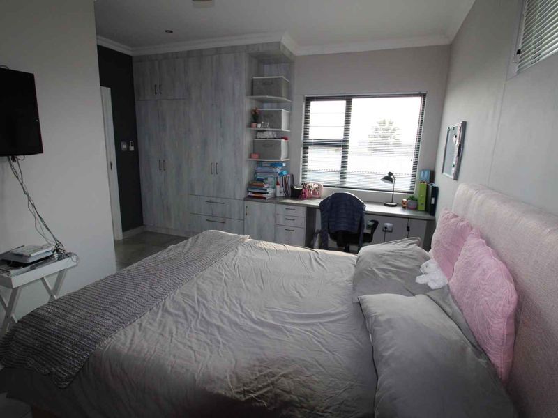 A well-lit bedroom featuring built-in cabinetry, a integrated desk workspace, and neutral finishes, providing a functional and organized living space.
