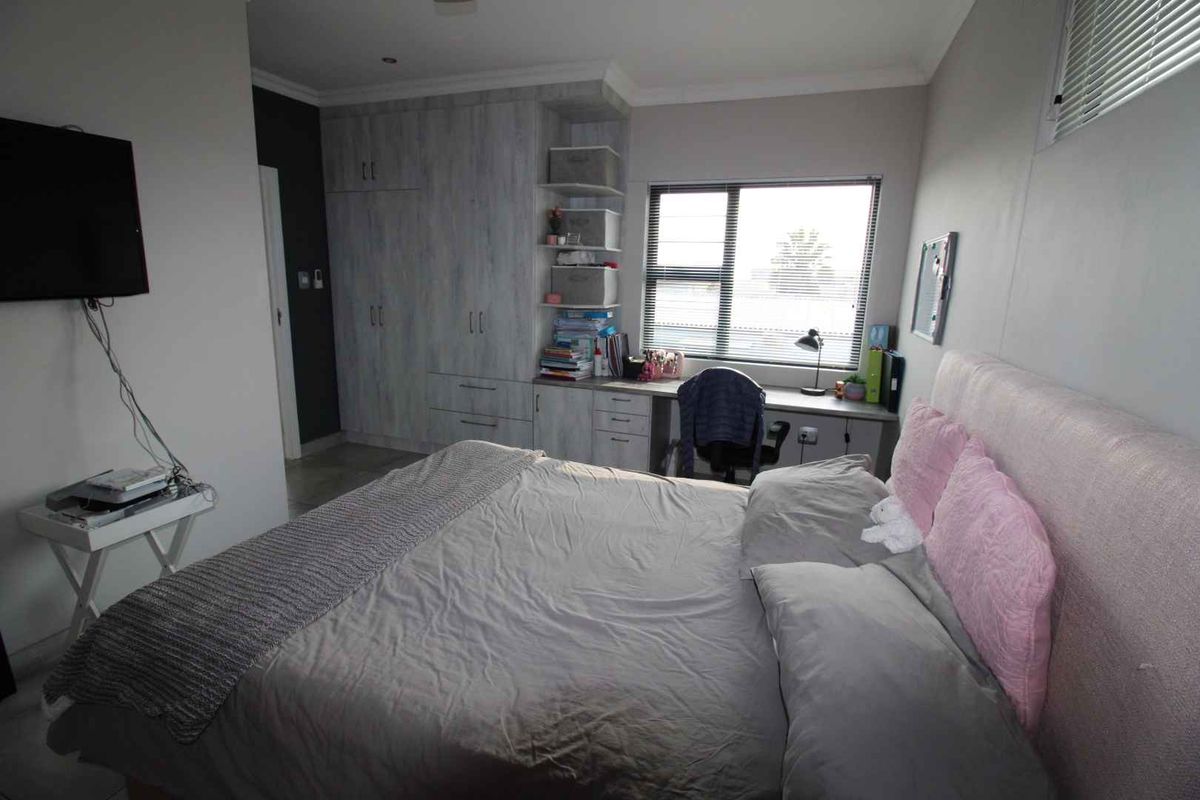 A well-lit bedroom featuring built-in cabinetry, a integrated desk workspace, and neutral finishes, providing a functional and organized living space.