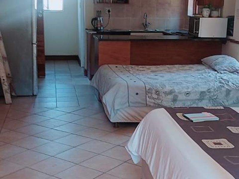 Open-plan studio apartment featuring a compact kitchen area with built-in cabinetry and tiled flooring throughout.