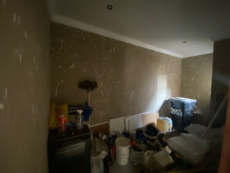 A utility space or storage room featuring recessed ceiling lighting and coving, currently in need of wall repairs and cosmetic refurbishment.