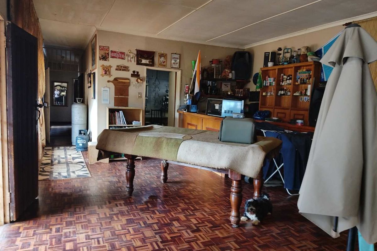A multi-purpose living area featuring traditional parquet flooring and direct access to adjacent rooms, offering a versatile space for entertainment or recreation.