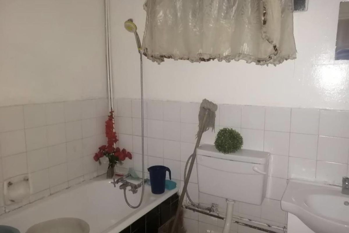 A functional bathroom featuring a standard bathtub with handheld shower attachment, a white ceramic toilet, and a wall-mounted basin.
