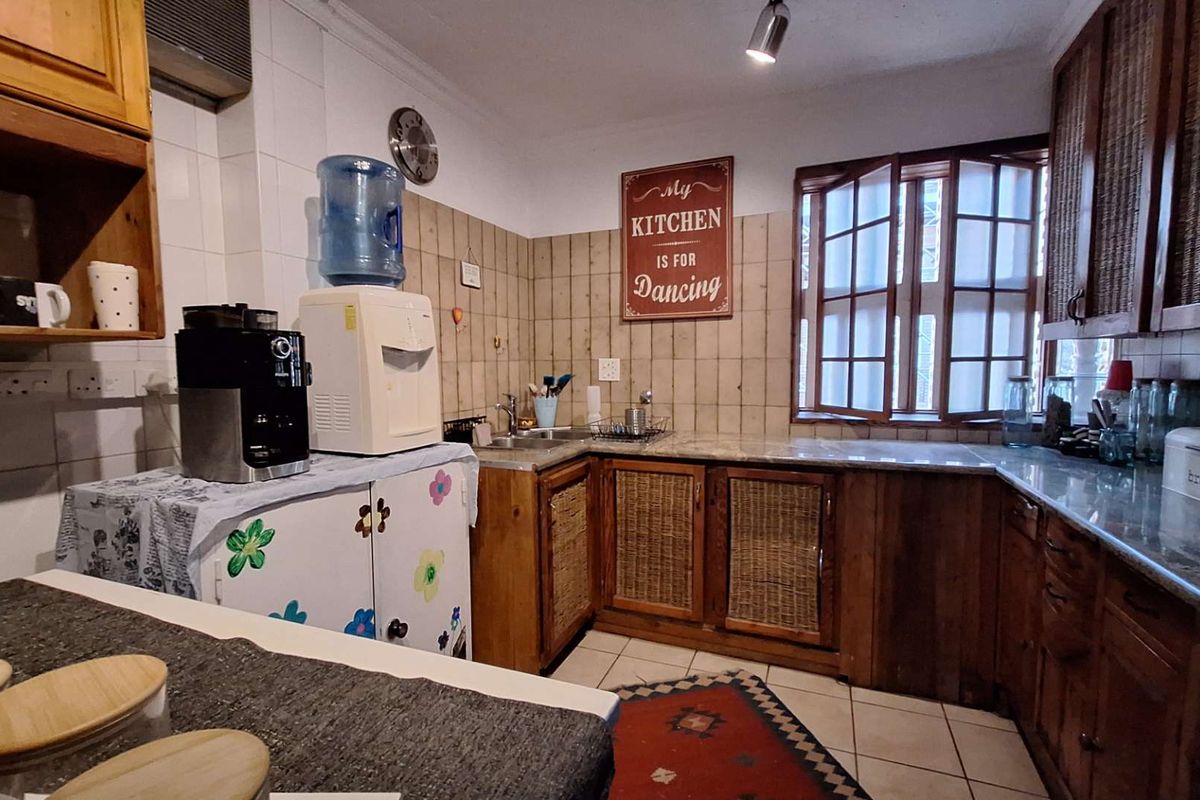 A functional kitchen featuring wooden cabinetry with woven inserts, stone-look countertops, and tiled splashbacks, offering a traditional aesthetic with ample storage space.