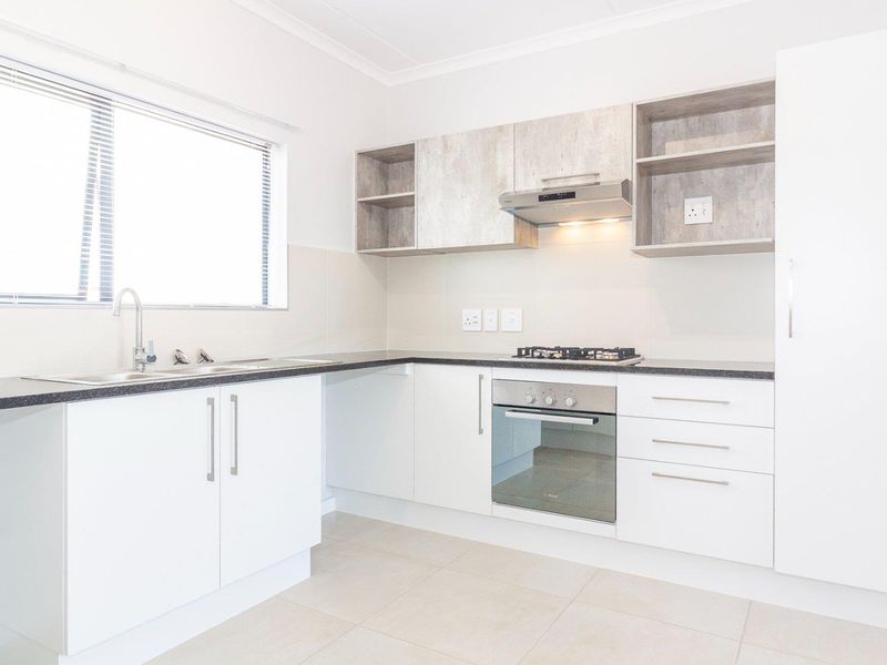 Modern kitchen featuring white cabinetry, laminate countertops, built-in oven, gas hob, extractor fan, and tiled flooring in a clean, well-maintained space.