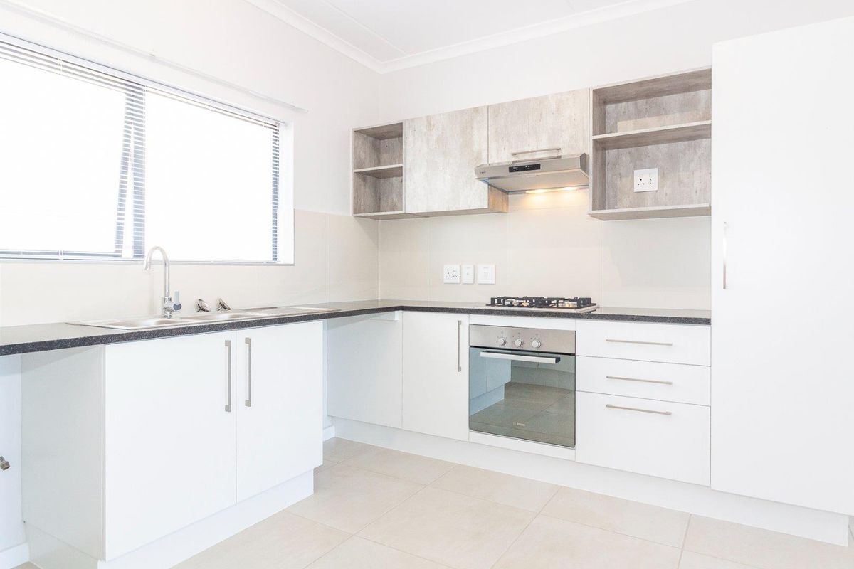 Modern kitchen featuring white cabinetry, laminate countertops, built-in oven, gas hob, extractor fan, and tiled flooring in a clean, well-maintained space.