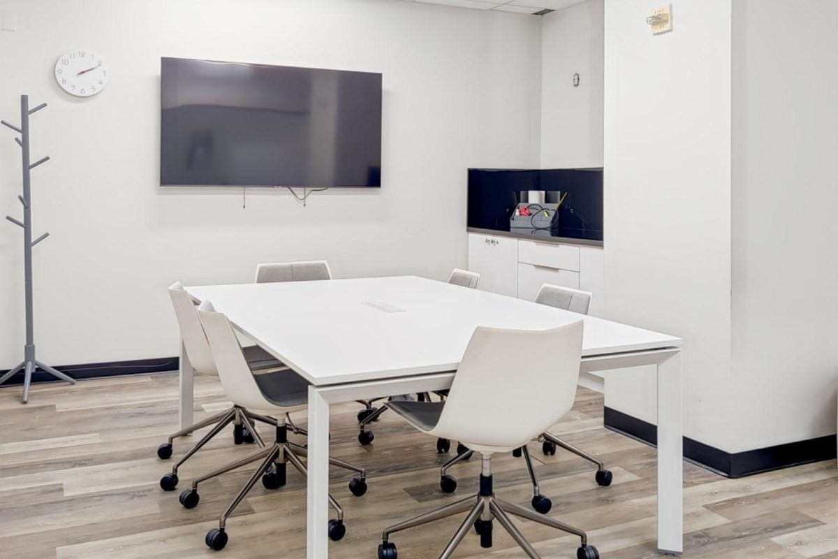 A modern office meeting room featuring laminate flooring, built-in cabinetry, and a suspended ceiling, providing a clean and professional workspace environment.