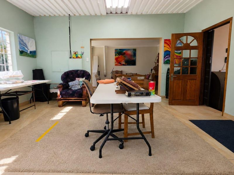 Spacious living area featuring tiled flooring, exposed beam ceiling, and a traditional timber door, offering a versatile layout with potential for modernization.