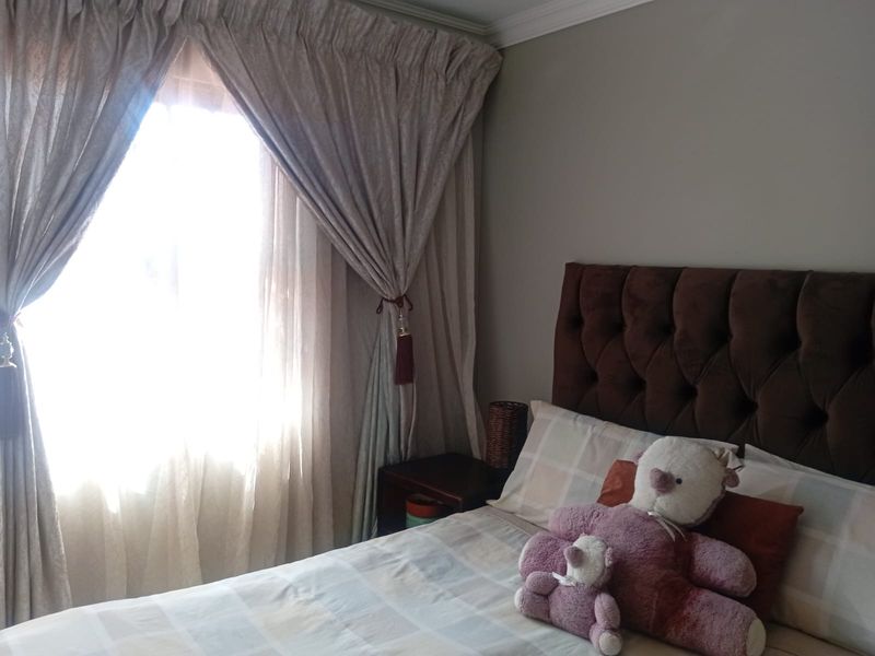 A cozy bedroom featuring neutral wall tones and classic crown molding, providing a comfortable and well-maintained sleeping space.