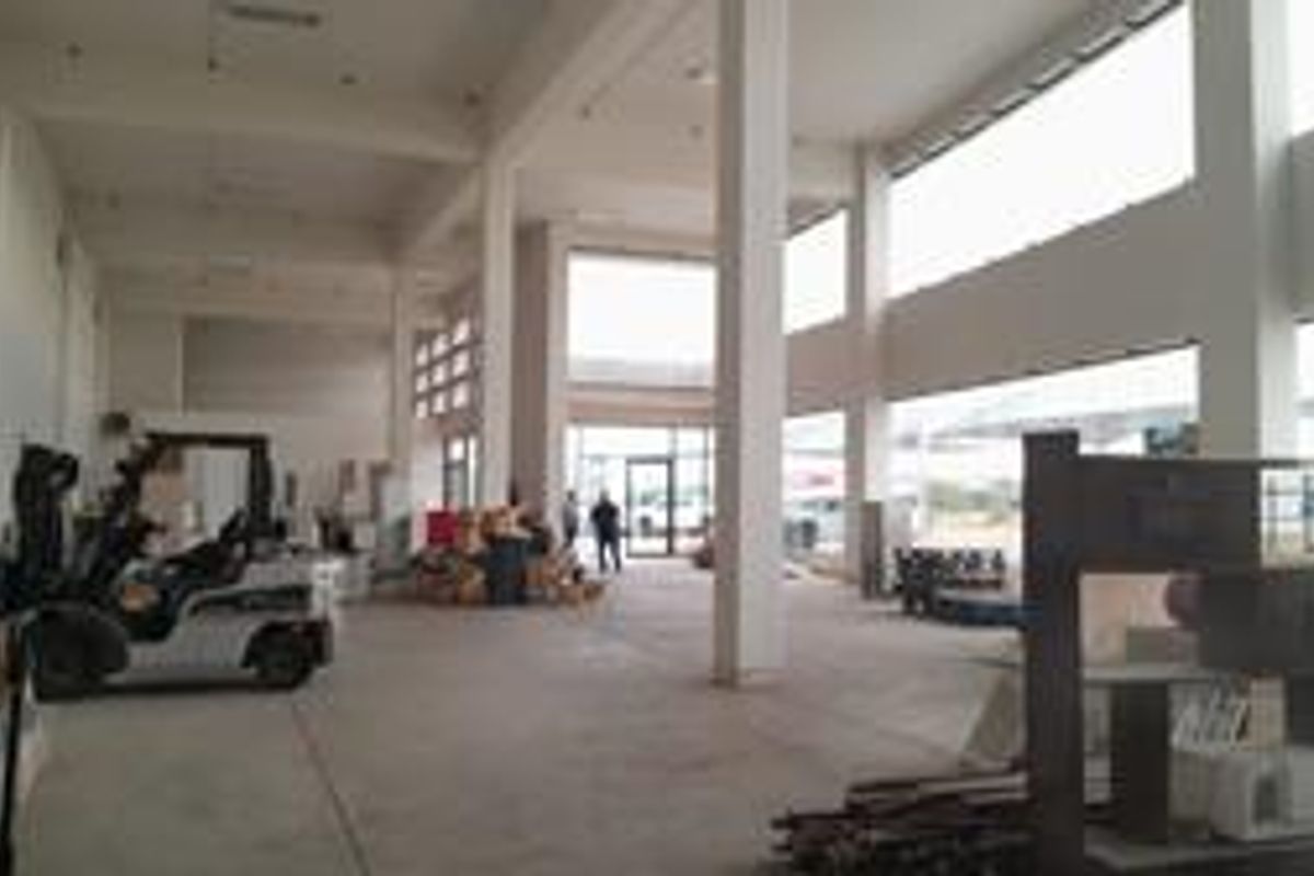 Spacious open-plan industrial unit featuring high ceilings, concrete flooring, and large windows providing ample natural light.