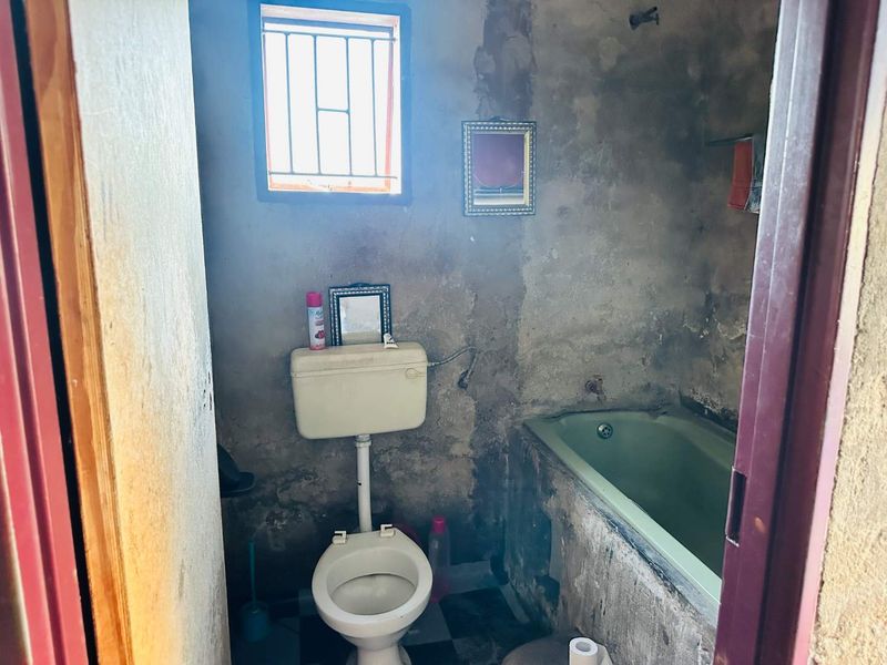 A bathroom in need of significant renovation, featuring a bathtub and toilet with severely deteriorated wall finishes.