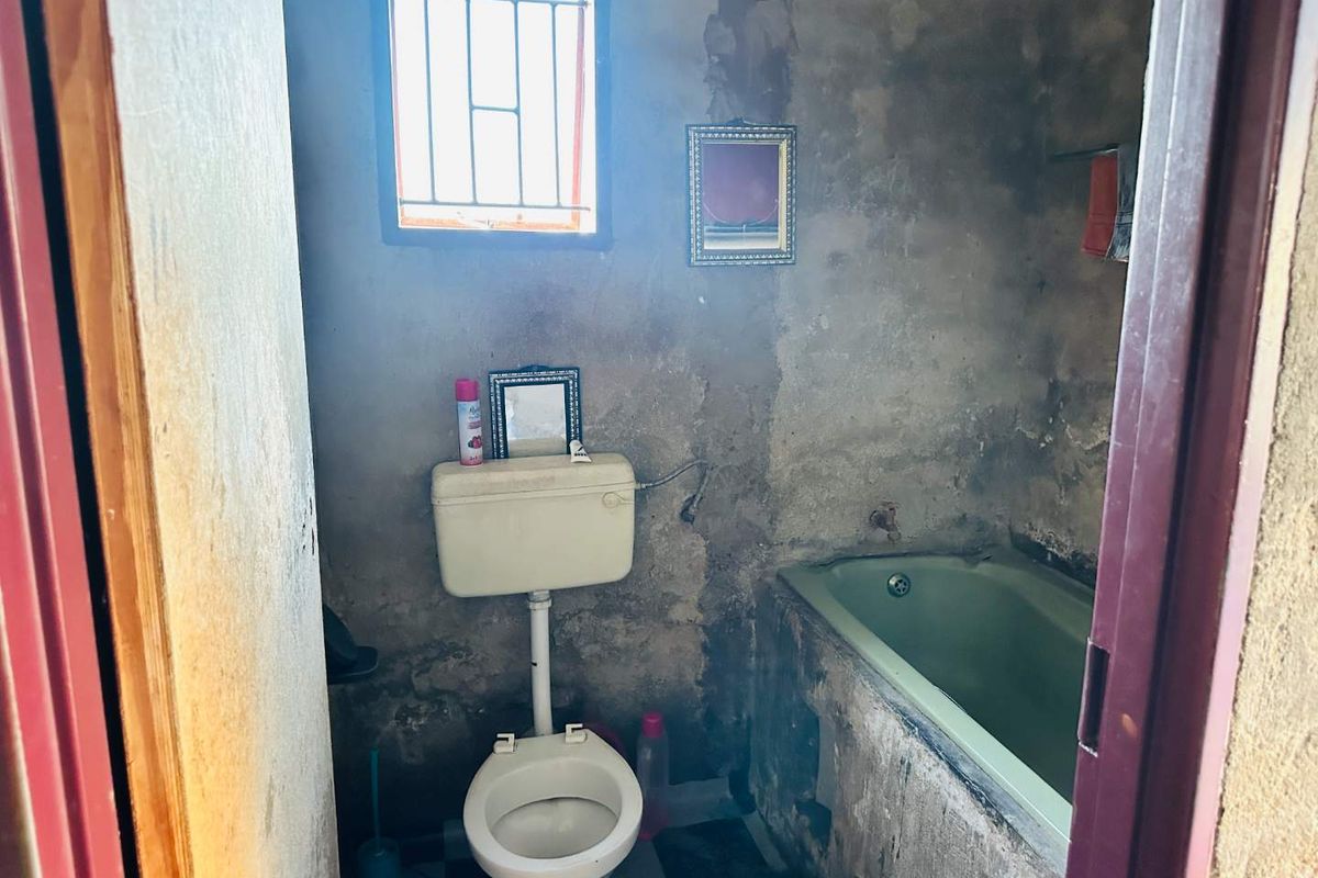 A bathroom in need of significant renovation, featuring a bathtub and toilet with severely deteriorated wall finishes.