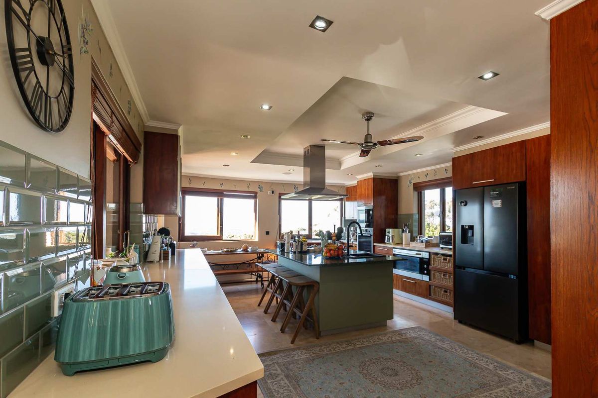 Spacious kitchen featuring a central island with stone countertops, wooden cabinetry, built-in appliances, and recessed lighting, offering a functional and well-lit cooking space.