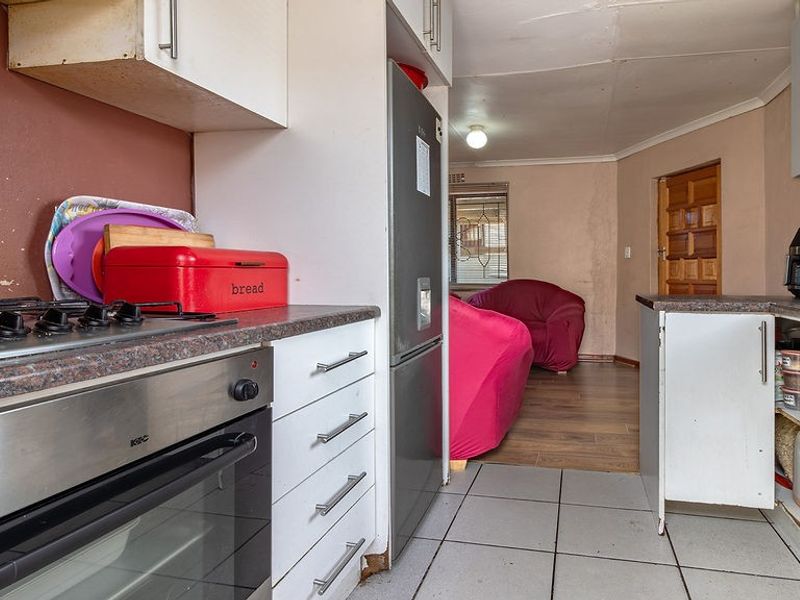 A functional kitchen featuring built-in cabinetry, laminate countertops, and a built-in oven with gas hob, showing signs of wear and requiring cosmetic updates.