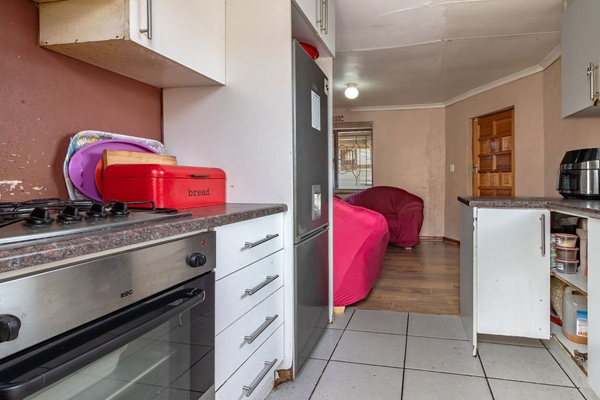 A functional kitchen featuring built-in cabinetry, laminate countertops, and a built-in oven with gas hob, showing signs of wear and requiring cosmetic updates.