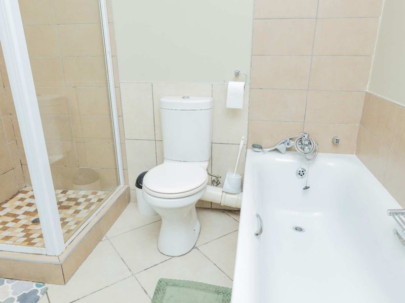 A functional bathroom featuring a shower enclosure, a standard bathtub, and a toilet with tiled finishes throughout.