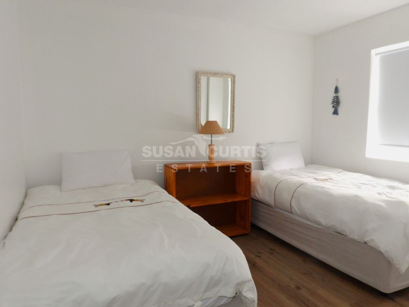 A simple bedroom featuring laminate flooring and a roller blind, providing a clean and functional space.