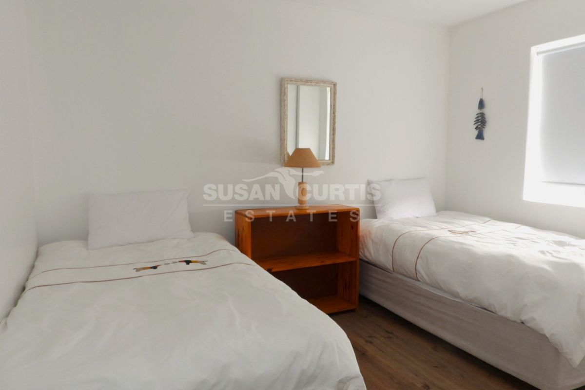 A simple bedroom featuring laminate flooring and a roller blind, providing a clean and functional space.