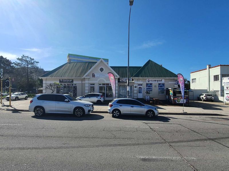 Front exterior view of a mixed-use commercial property featuring a pitched roof, paved parking area, and prominent street-facing signage.