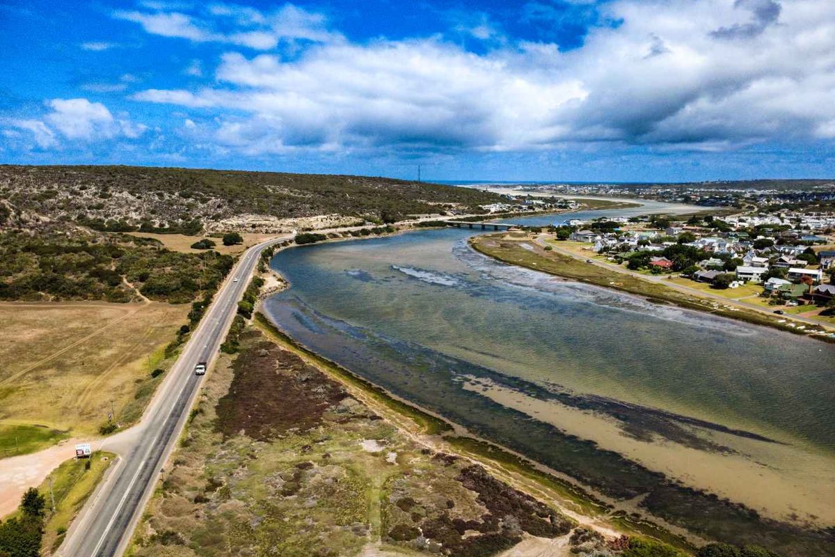 Aerial view of the coastal landscape, featuring a river estuary, surrounding natural vegetation, and nearby residential development.