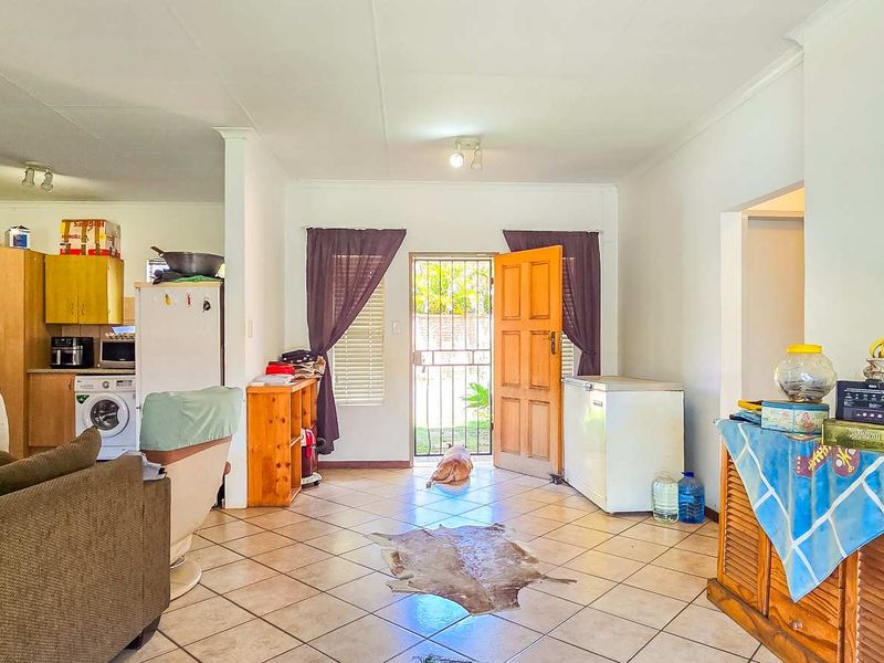 Open plan living area featuring tiled flooring and an integrated kitchen space with direct access to the exterior through a security gate.