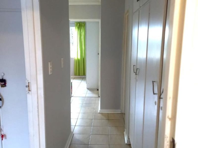 A functional hallway featuring tiled flooring and extensive built-in storage cupboards, providing a clean and neutral transition space within the townhouse.