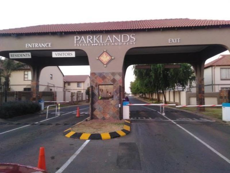 The main entrance gatehouse of Parklands Estate, featuring controlled boom gate access for residents and visitors with stone-clad pillars and a tiled roof.