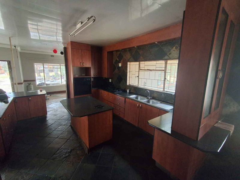 Spacious kitchen featuring extensive built-in cabinetry, stone countertops, a double sink, and a built-in oven, finished with slate tile flooring.