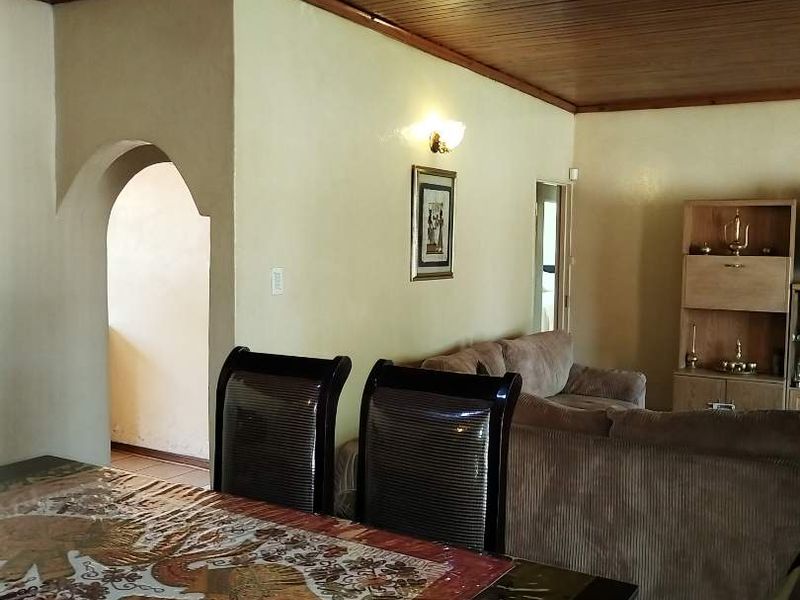 Open plan living and dining area featuring a timber tongue and groove ceiling, ceramic tiled flooring, and a distinctive arched doorway.