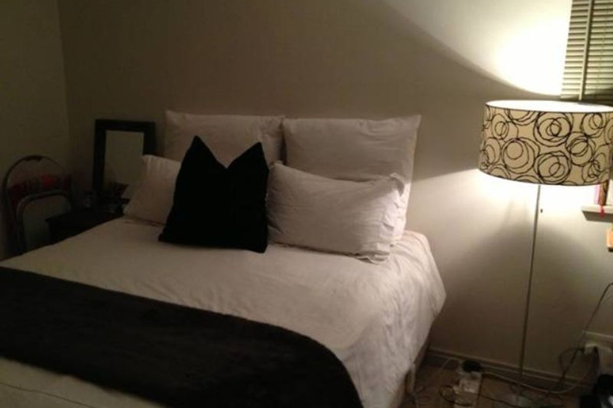 A bedroom featuring neutral wall finishes and venetian blinds, providing a functional sleeping space.