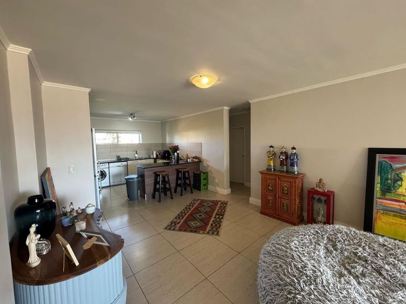 Open-plan living and kitchen area featuring tiled flooring, a central kitchen island, and integrated cabinetry with built-in appliances.