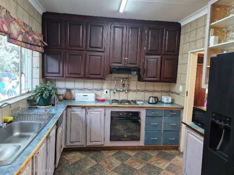 A functional kitchen featuring dark upper cabinetry, contrasting lower cabinets, built-in oven and hob, and tiled backsplash with durable flooring.