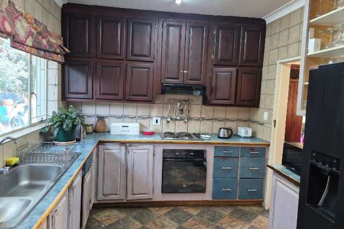 A functional kitchen featuring dark upper cabinetry, contrasting lower cabinets, built-in oven and hob, and tiled backsplash with durable flooring.