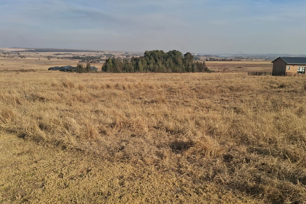 A wide-angle view of expansive, undeveloped residential land featuring natural grassland and distant tree clusters under a clear sky.