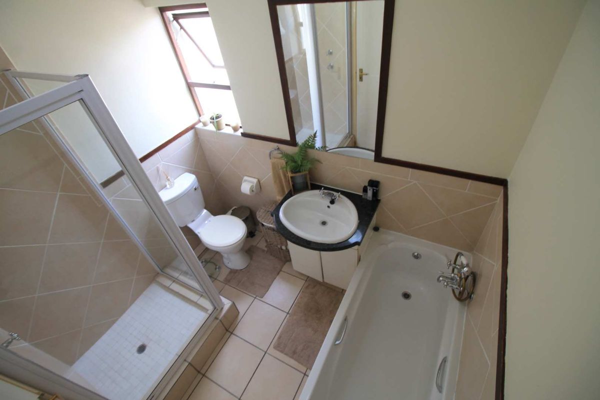 A functional bathroom featuring a separate shower enclosure, a bathtub, a vanity basin with a granite countertop, and a toilet.