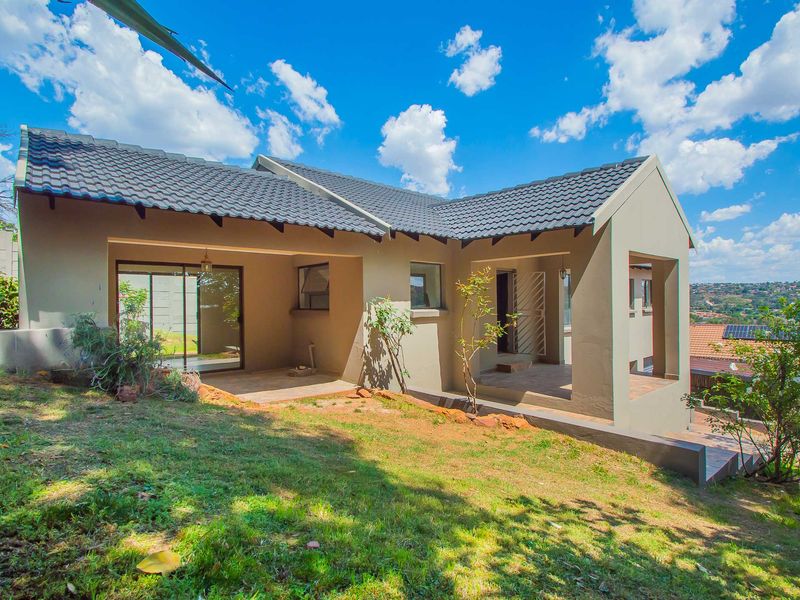 Rear view of the house featuring a covered patio, tiled roof, and sliding glass doors leading to the garden area.
