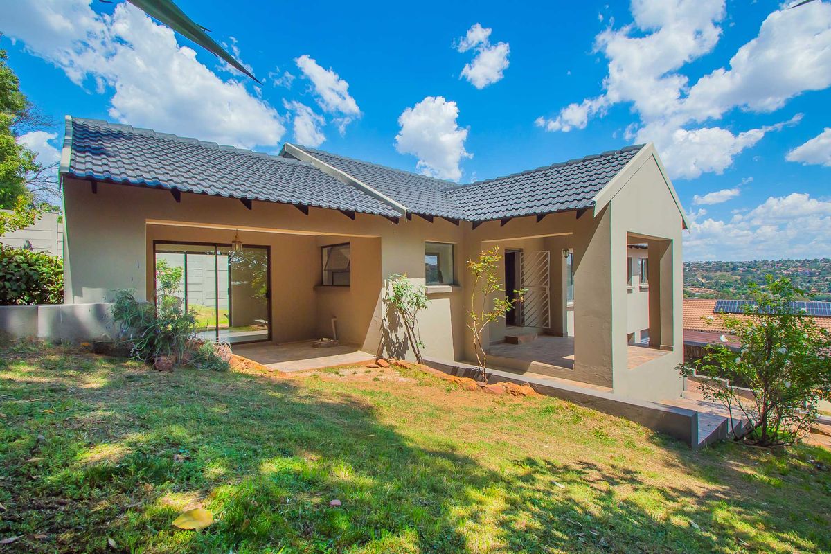 Rear view of the house featuring a covered patio, tiled roof, and sliding glass doors leading to the garden area.