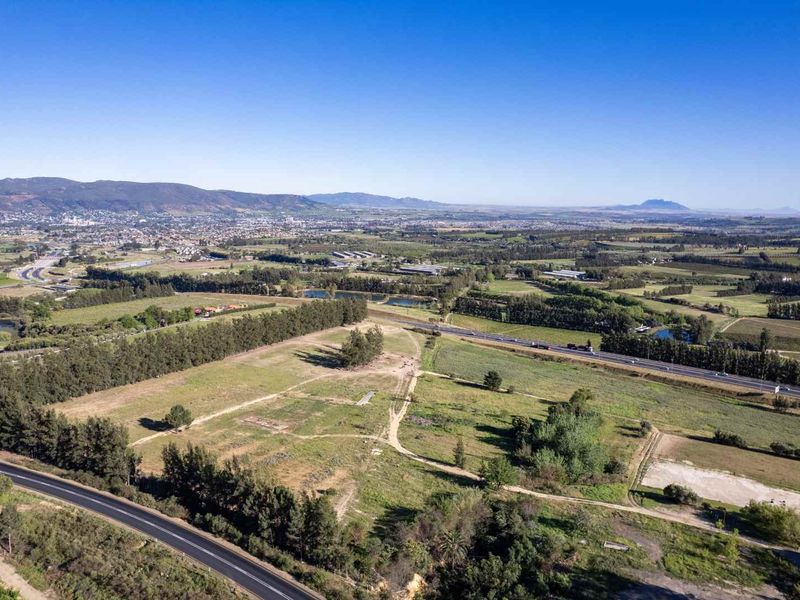An aerial view of a large farm property featuring open fields, surrounding landscape, and proximity to major road infrastructure.