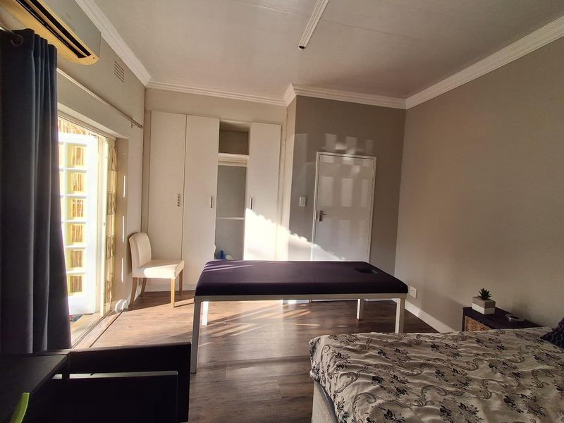 A bedroom featuring laminate flooring, built-in cupboards, air conditioning, and direct access to an outdoor area through french doors.