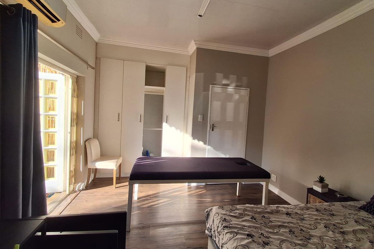 A bedroom featuring laminate flooring, built-in cupboards, air conditioning, and direct access to an outdoor area through french doors.