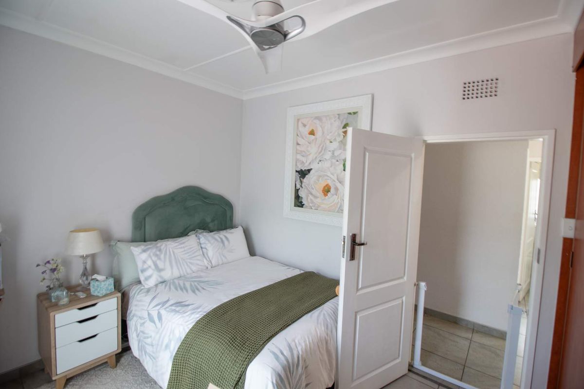 A well-maintained bedroom featuring a ceiling fan, decorative coving, and a ventilation grille, providing a comfortable and functional living space.