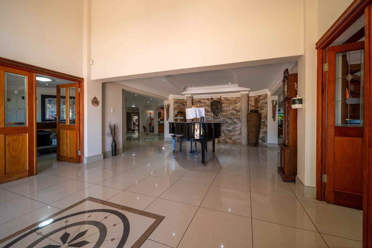 Spacious living area featuring polished tiled flooring, a decorative floor inlay, and a prominent stone feature wall with recessed downlighting.
