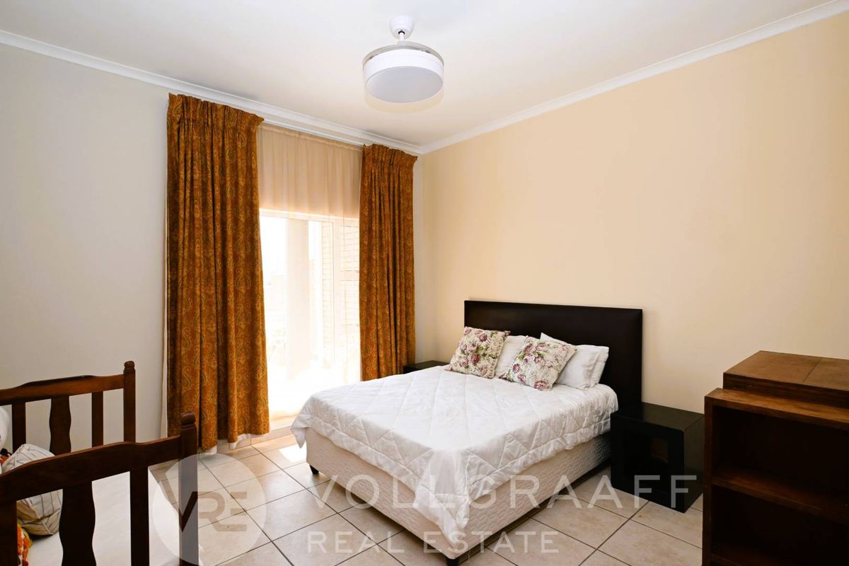 A bedroom featuring tiled flooring, a ceiling light fixture, and a sliding door providing access to an outdoor area.