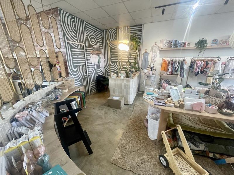 A retail space featuring a polished concrete floor, exposed brick accents, a tiled service counter, and a suspended ceiling.