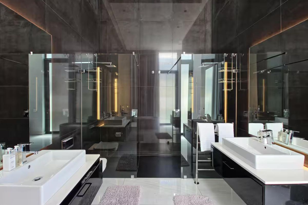 Modern luxury bathroom featuring a double vanity with vessel sinks, sleek black cabinetry, and a spacious walk-in shower with glass enclosure.
