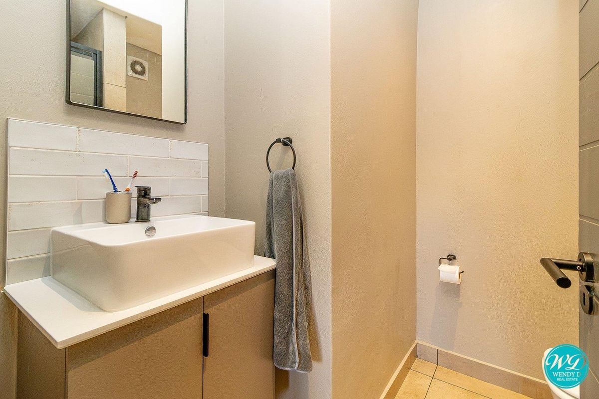 A modern bathroom featuring a vessel sink vanity with tiled splashback, extractor fan, and neutral wall finishes.