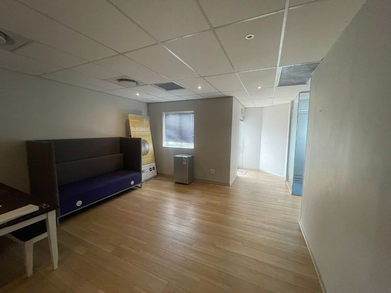 A functional office space featuring a suspended ceiling with recessed lighting, laminate flooring, and a glass partition wall, providing a clean and professional work environment.