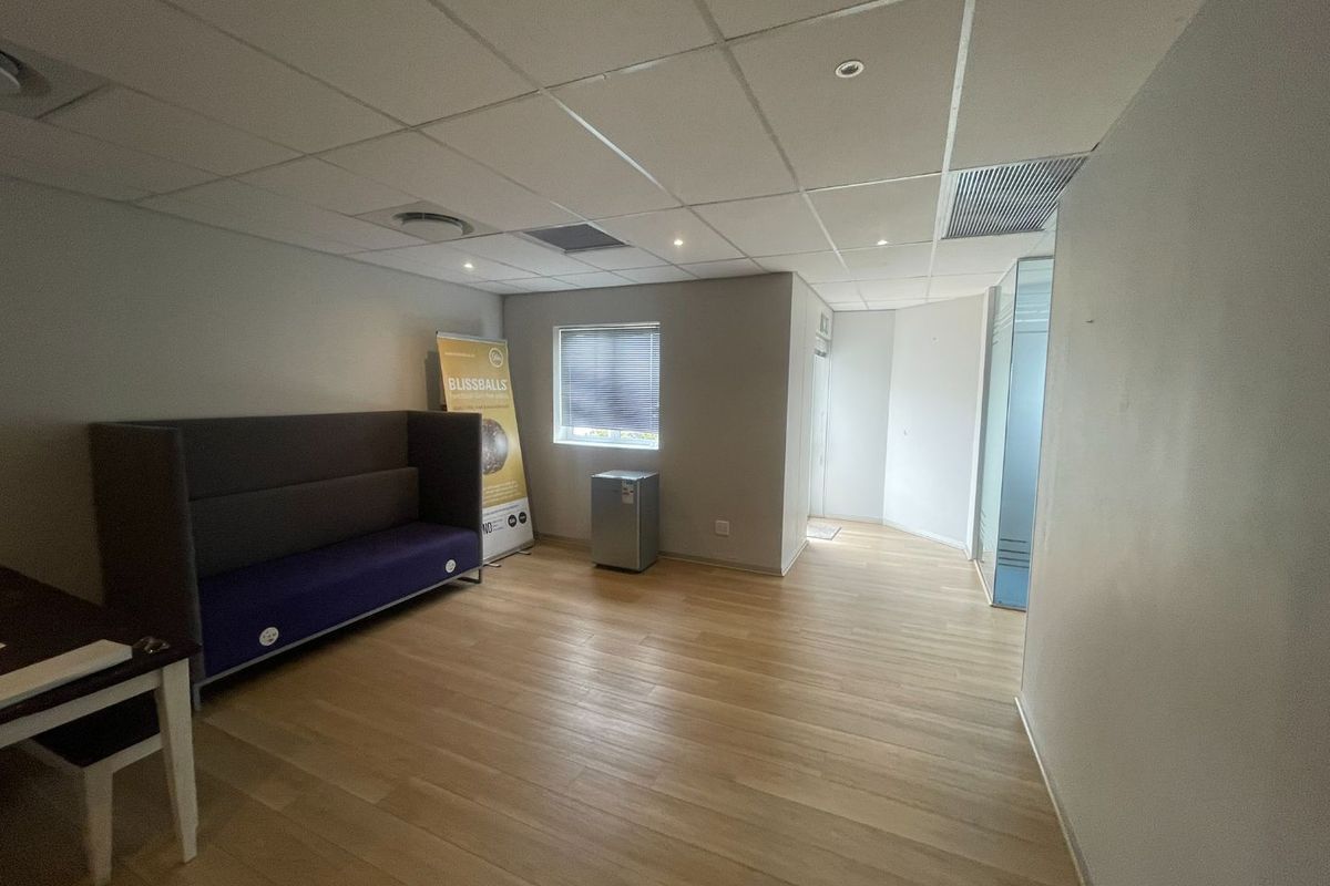 A functional office space featuring a suspended ceiling with recessed lighting, laminate flooring, and a glass partition wall, providing a clean and professional work environment.