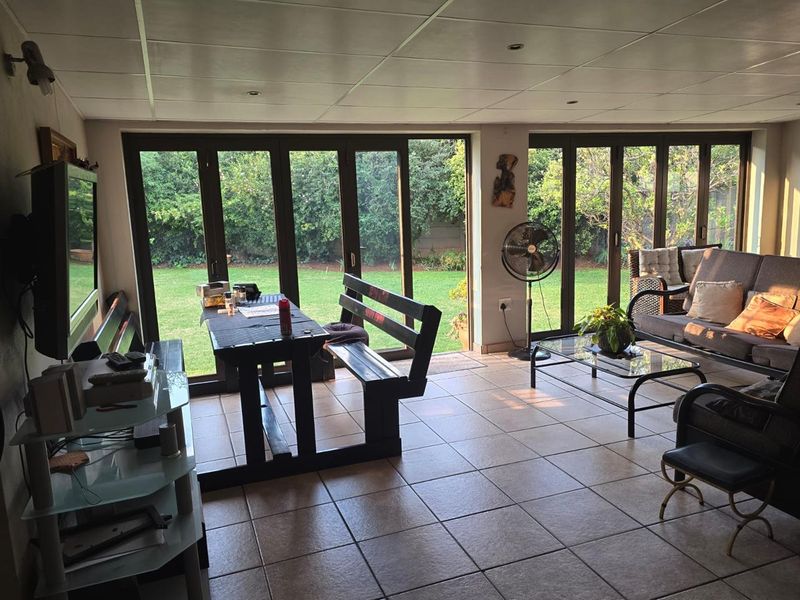 A spacious enclosed patio featuring tiled flooring and large bi-fold glass doors that provide seamless access to the garden.