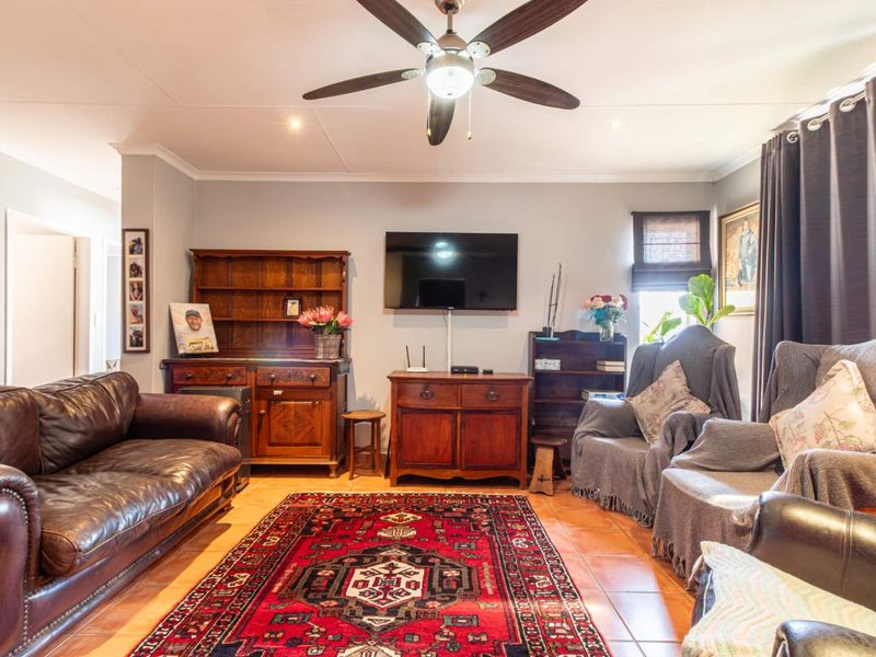 A comfortable living room featuring tiled flooring, a central ceiling fan, and recessed lighting, providing a functional and inviting space for relaxation.