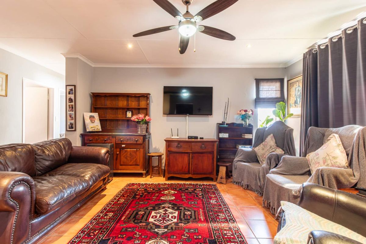 A comfortable living room featuring tiled flooring, a central ceiling fan, and recessed lighting, providing a functional and inviting space for relaxation.